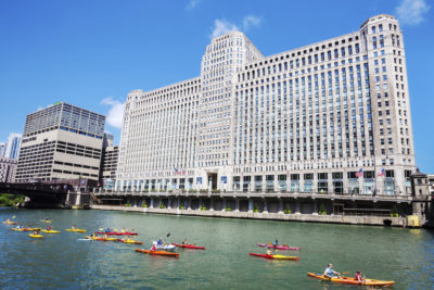 "Chicago, USA - July 28, 2012: Kayaks on the Chicago River in front of Merchandise Mart (built 1930), downtown Chicago. People in a group of colorful kayaks on a sunny day."